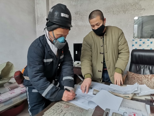 兴安矿动力科排水队井下水泵司机朱甲民（图左）在清静确认本上签字