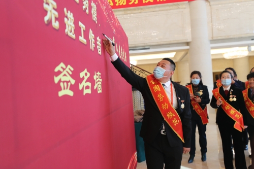 图为天下劳动模范李凤明在署名墙上签字
